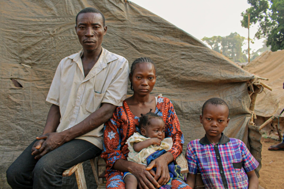 El refugiado centroafricano Boris, de 37 años, sentado junto a su esposa Christine y sus dos hijos fuera de su alojamiento improvisado en el pueblo de Ndu en la República Democrática del Congo.