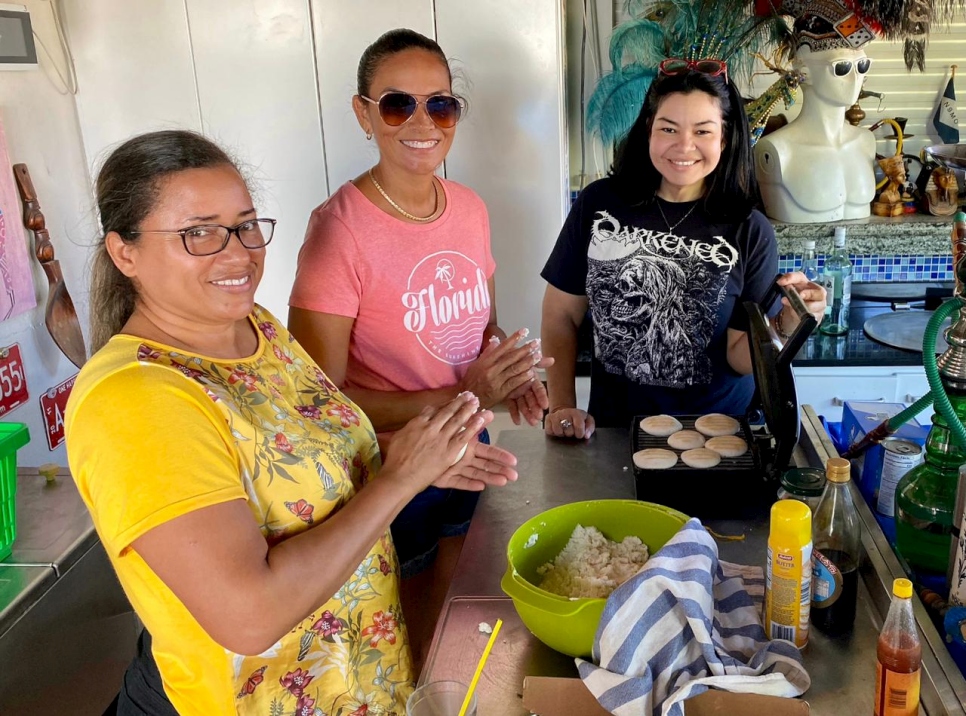 Tres mujeres están preparando arepas en una cocina.