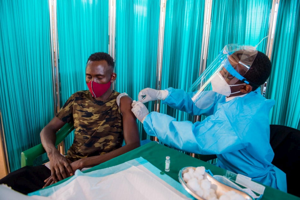 Un refugiado en el Centro de Tránsito de Gashora, en Ruanda, recibe la vacuna contra la COVID-19.