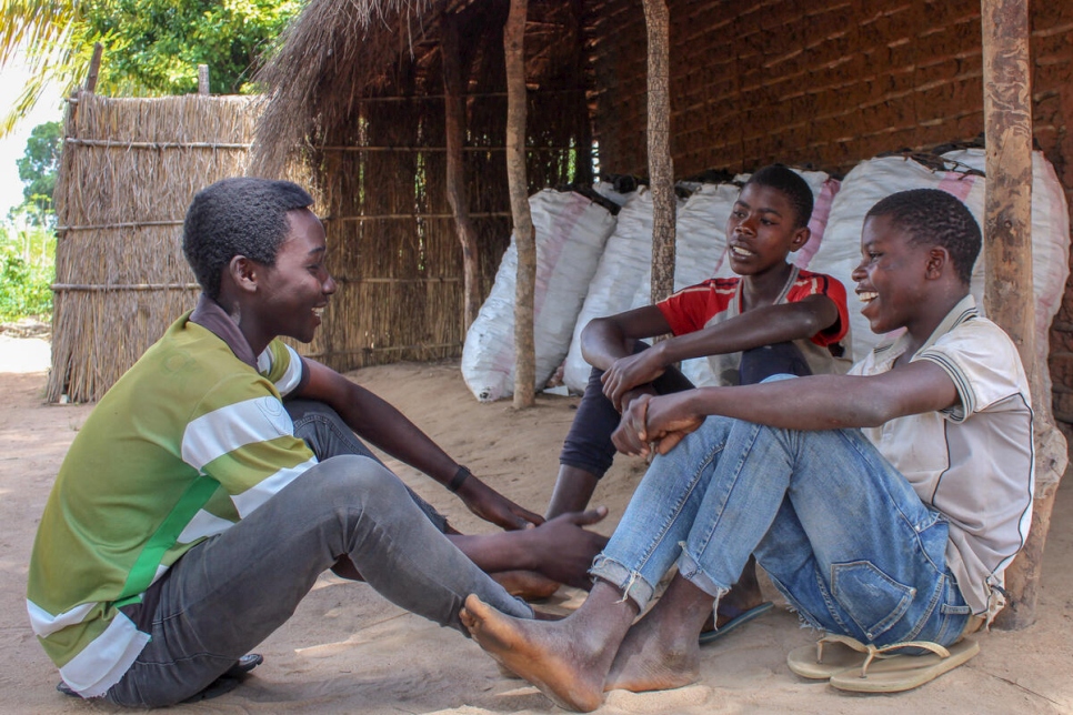 (De izquierda a derecha) Momad (de 17 años), su hermano Abdala (de 15 años y camiseta blanca) y su amigo Bakar (de 13 años) conversan tranquilamente en el asentamiento de Ndele, en Montepuez, Mozambique.