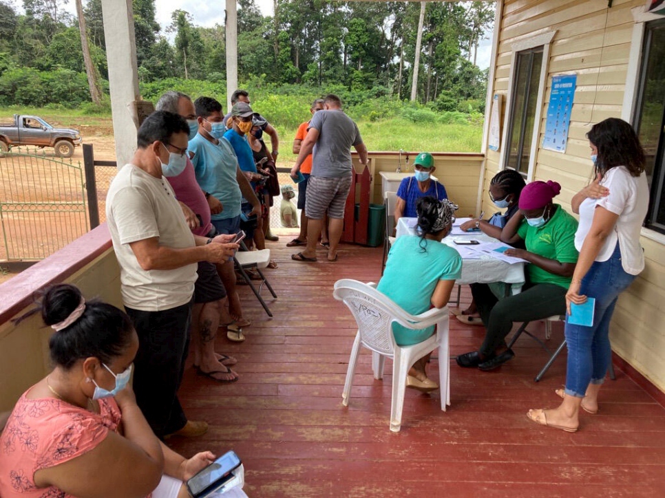 Personas desplazadas e integrantes de la comunidad local hacen fila para recibir la vacuna contra la COVID-19 en Guyana.