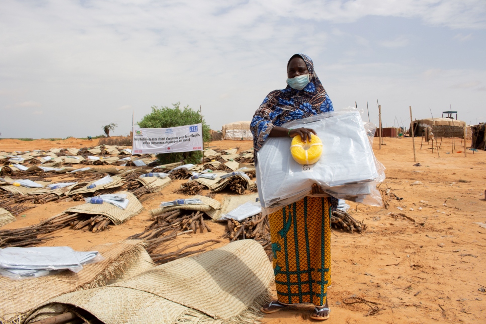 Aissa Modi, una nigerina desplazada interna de 35 años y madre de cuatro hijos, se encuentra junto a una distribución de leña en Zarmaganda, Ouallam, con un kit de alojamiento temporal distribuido por ACNUR. Hace tres meses huyó de la aldea de N'zouett, cerca de la frontera con Malí, en busca de seguridad.