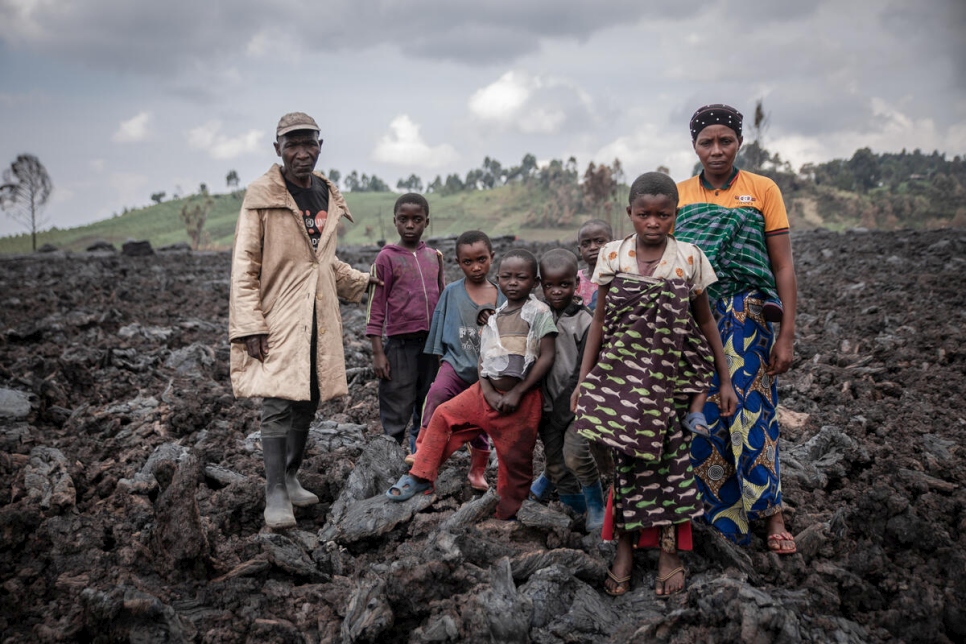 Jean y Esperance Muhoza y sus siete hijos están parados sobre la roca volcánica donde solía estar su casa.
