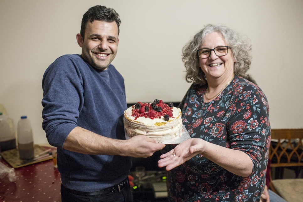 Hani Arnout, de 34 años, originario de Siria, acepta un pastel de la residente local Helen Stoneman en su casa de Ottery St Mary, Devon, Reino Unido, en marzo de 2019. 