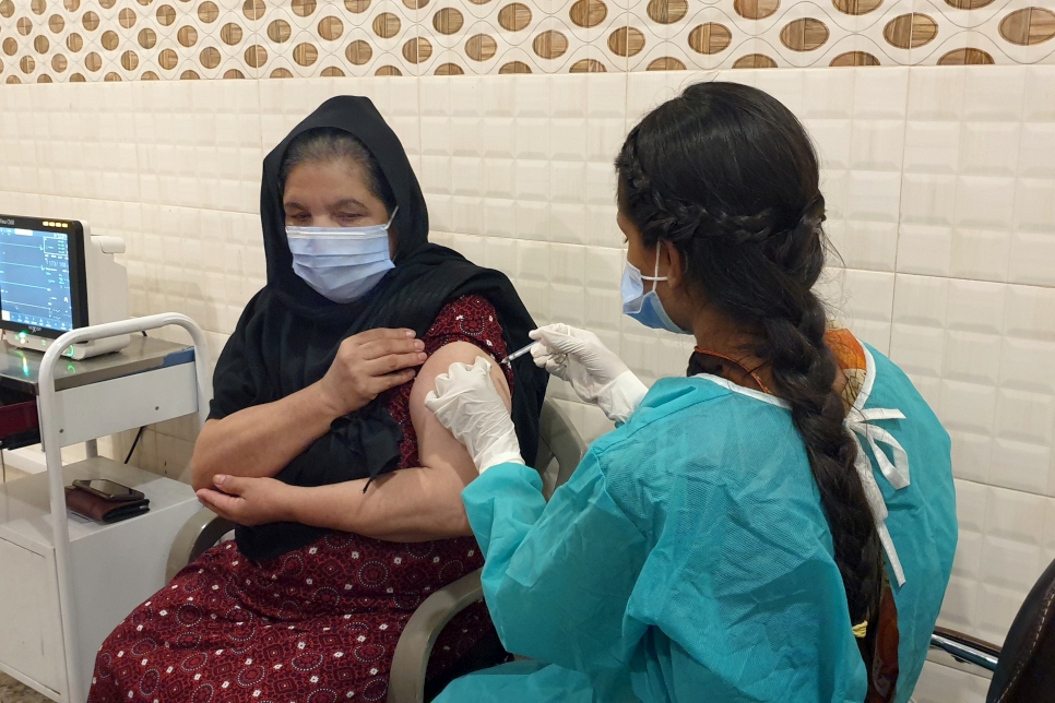 Nafeesa, una mujer refugiada afgana de 48 años, recibe la vacuna contra la COVID-19 en el Centro de Vacunación de la Media Luna Roja en Rawalpindi, Punjab (Pakistán).