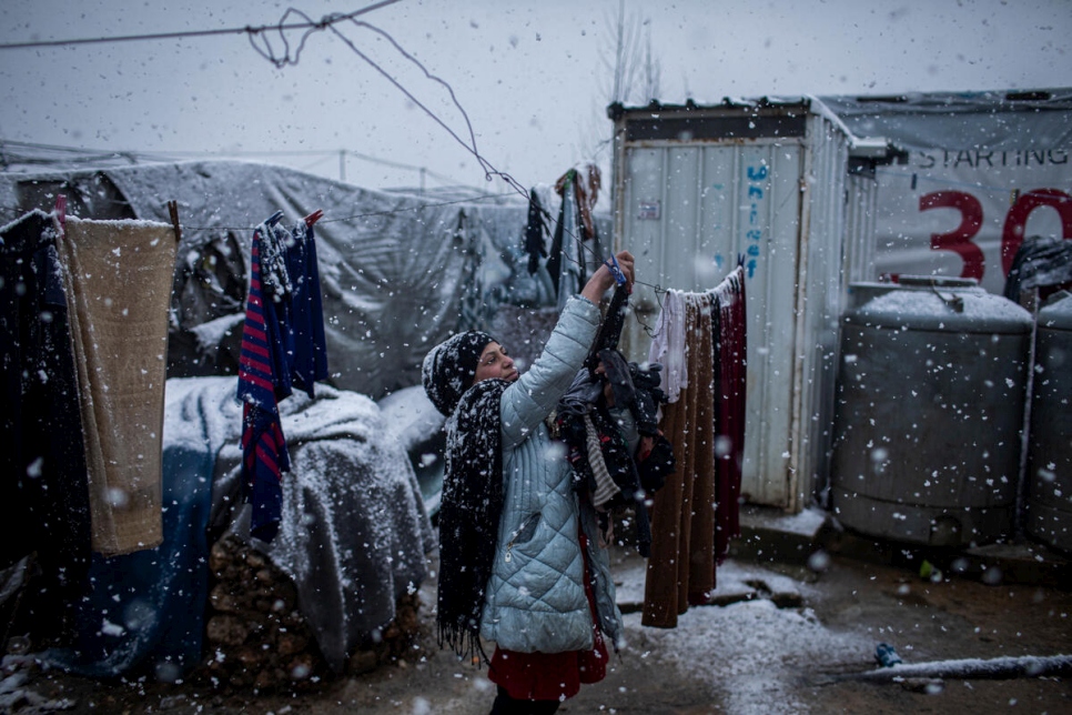 Joven siria refugiada recoge ropa lavada en medio de una tormenta en un asentamiento informal en el Valle de la Becá, Líbano, en febrero de 2021.