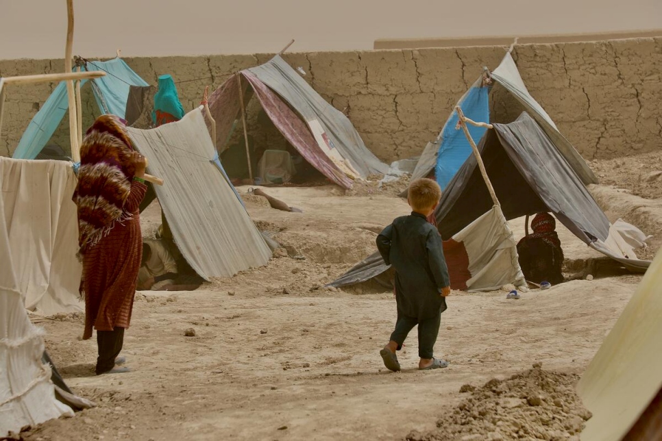 Una mujer y un niño caminan entre tiendas improvisadas en el campamento para personas desplazadas internas de Nawabad Farabi-ha, en Mazar-e Sharif, norte de Afganistán.