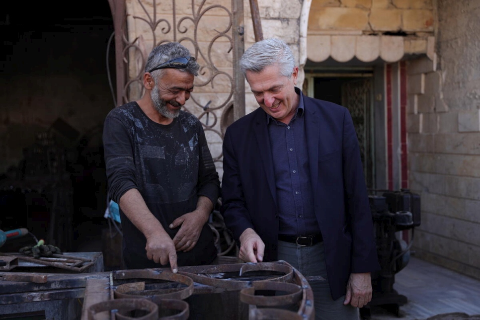El Alto Comisionado de la ONU para los Refugiados, Filippo Grandi (a la derecha), se reúne con el herrero ex desplazado Wasel fuera de su taller en Talbiseh, Siria.