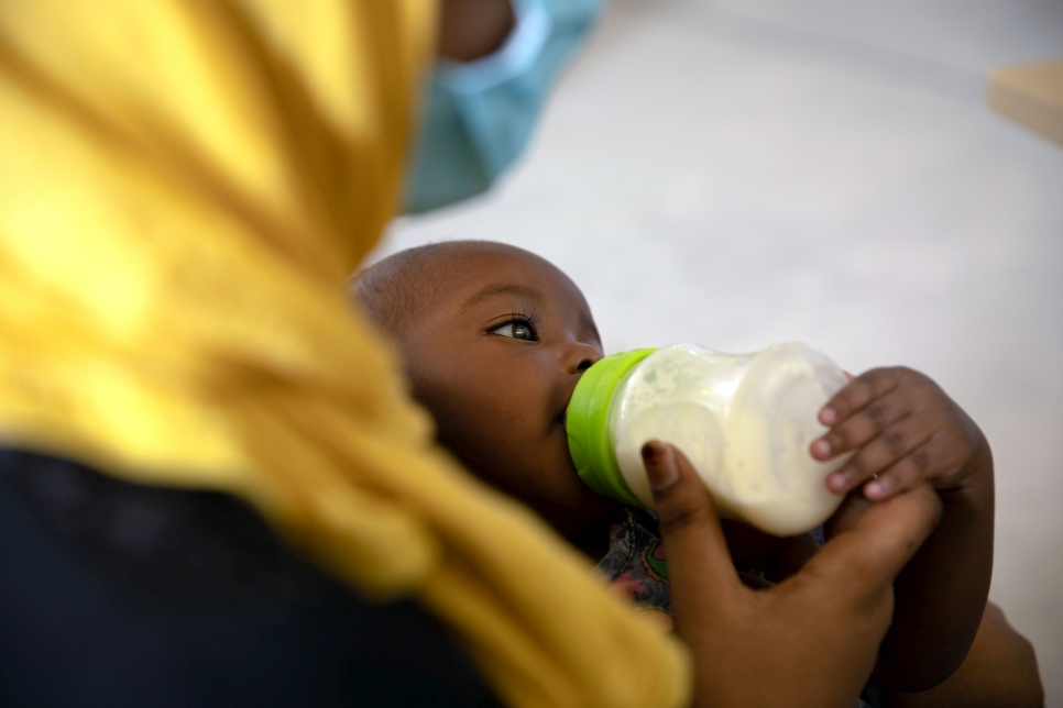 Una refugiada alimenta a su bebé mientras espera para recibir asistencia en una distribución de ayuda organizada por ACNUR y sus socios en Trípoli, Libia.