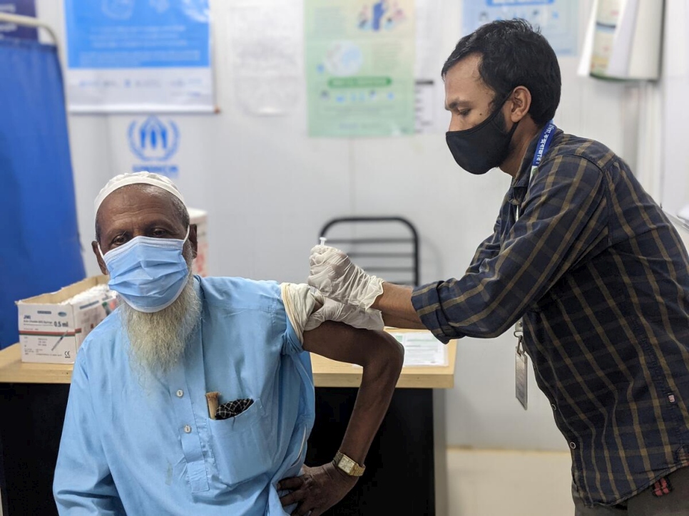 Un refugiado recibe una dosis de vacuna contra la COVID-19.