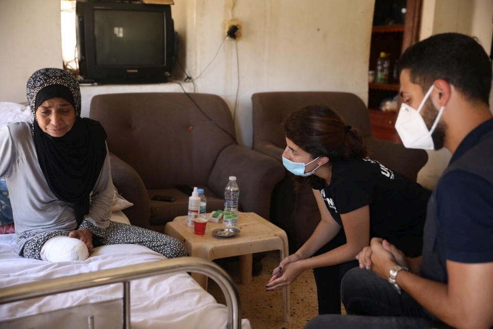 Aliyah (a la izquierda), quien tuvo que enfrentarse a las limitaciones de acceso a su casa en Sarafand, Líbano tras la amputación de su pierna, se reúne con visitantes de ACNUR y su socio para hablar de la renovación de la construcción.