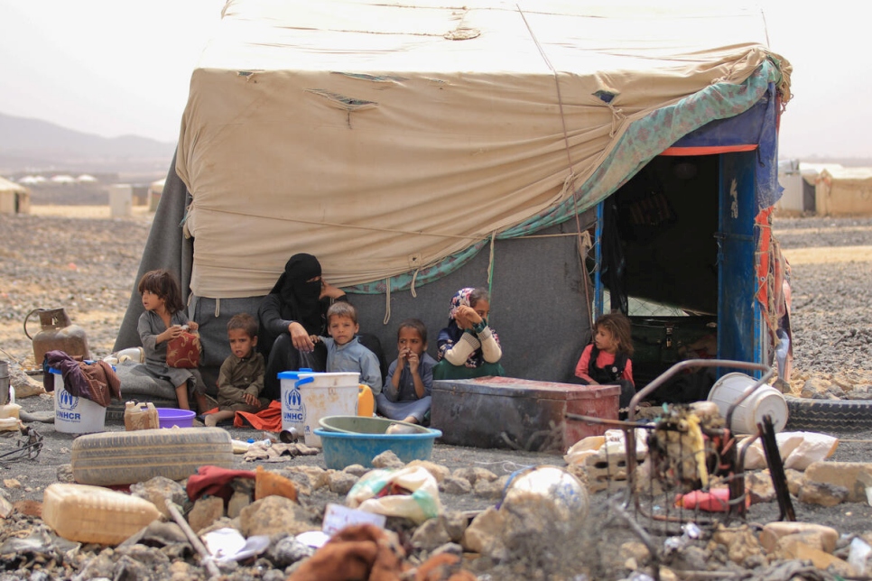 Una familia yemení desplazada interna sentada frente a su alojamiento en el campamento de Al-Suwaidan en la ciudad de Marib, Yemen, junio de 2021.