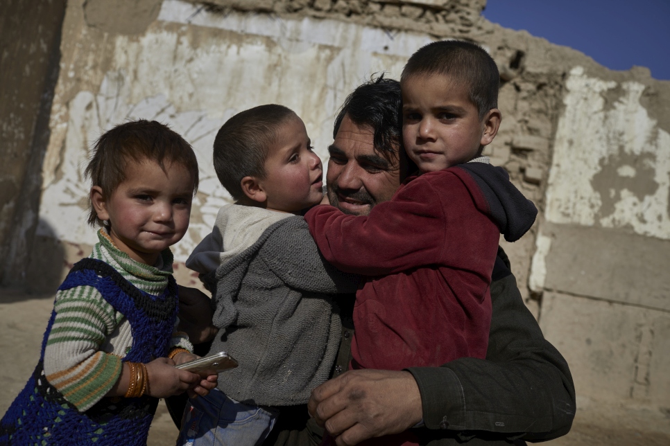 Un padre afgano desplazado y tres de sus hijos en su hogar temporal en Kariz-e-Meer, a las afueras de Kabul. La familia huyó del norte de Kunduz en mayo de 2021 después de que su casa fuera destruida por los combates.