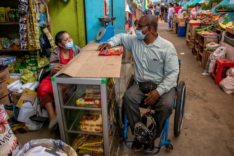 Omar, un colombiano refugiado con discapacidad, conversa con una mujer con discapacidad en el mercado municipal en Esmeraldas, Ecuador (abril de 2021)