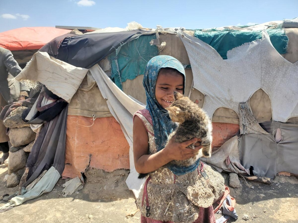 Niña yemení juega con un gatito en el asentamiento que ha dado acogida a personas desplazadas internas en Saná, Yemen (noviembre de 2021).