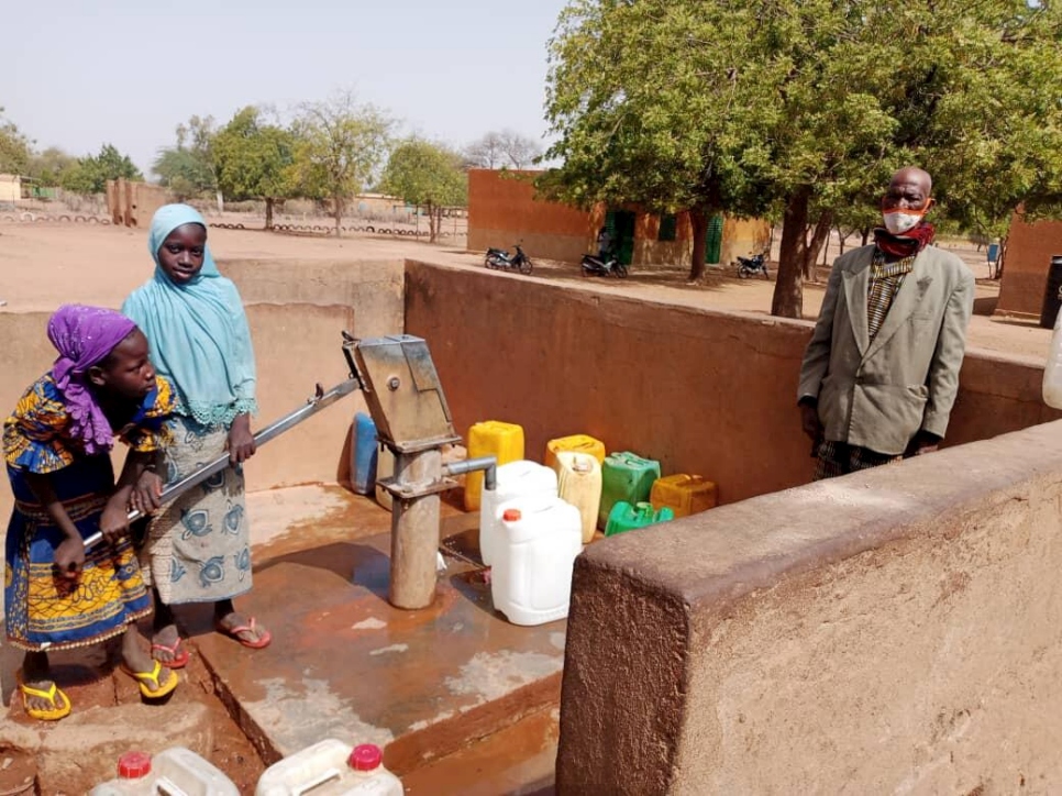 Lambda y dos de sus nietas extraen agua para las familias desplazadas que viven en su comunidad.