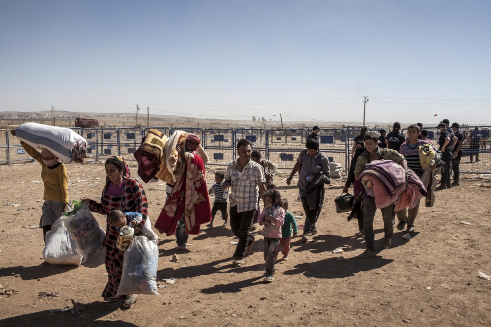 Personas refugiadas kurdas sirias cruzan la frontera de Siria a Turquía luego de huir de los combates entre las fuerzas kurdas e ISIS en torno a la ciudad de Kobane, al noreste de Siria.