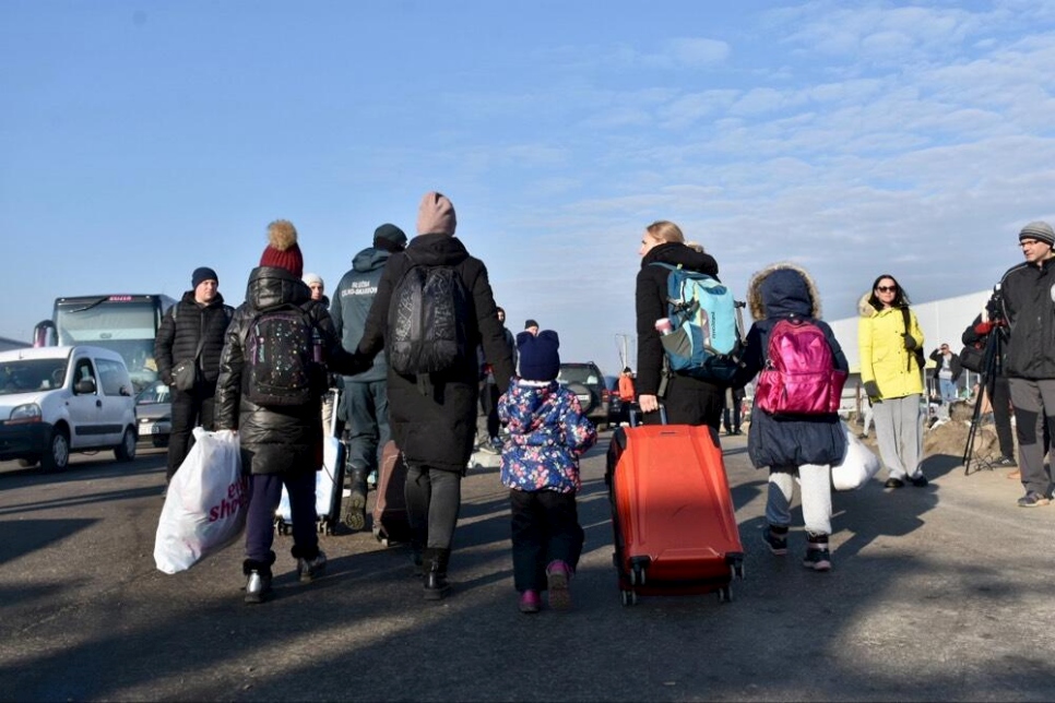 Familias cargan sus pertenencias a través del paso fronterizo de Zosin, en Polonia, luego de huir de Ucrania.