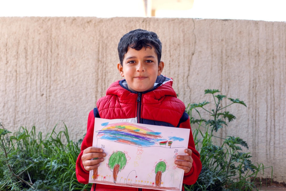 Ahmed, de 8 años, quien nació en Jordania en 2013, sostiene su dibujo de arcoíris sobre Siria.