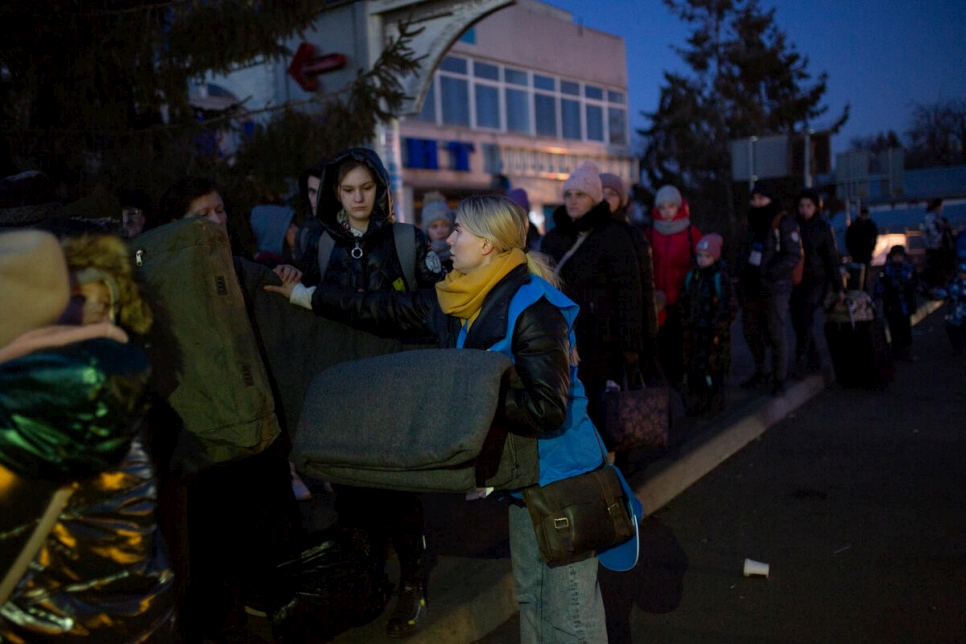 Personal de ACNUR distribuye mantas térmicas en el puesto fronterizo de Shehyni a los desplazados de Ucrania que aguardan para cruzar a Polonia.