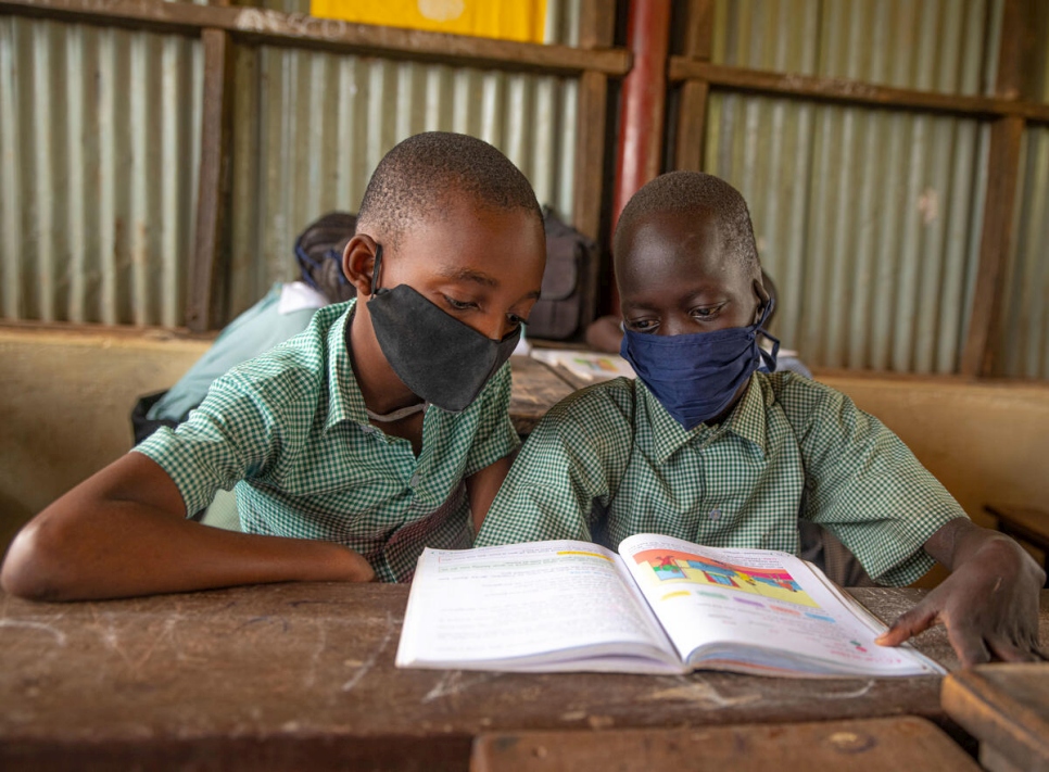 Samuel (derecha), un refugiado de 9 años de Sudán del Sur, y David, un refugiado congoleño de 11 años, comparten libro de texto en un club escolar en el campamento de refugiados de Kakuma, en Kenia.
