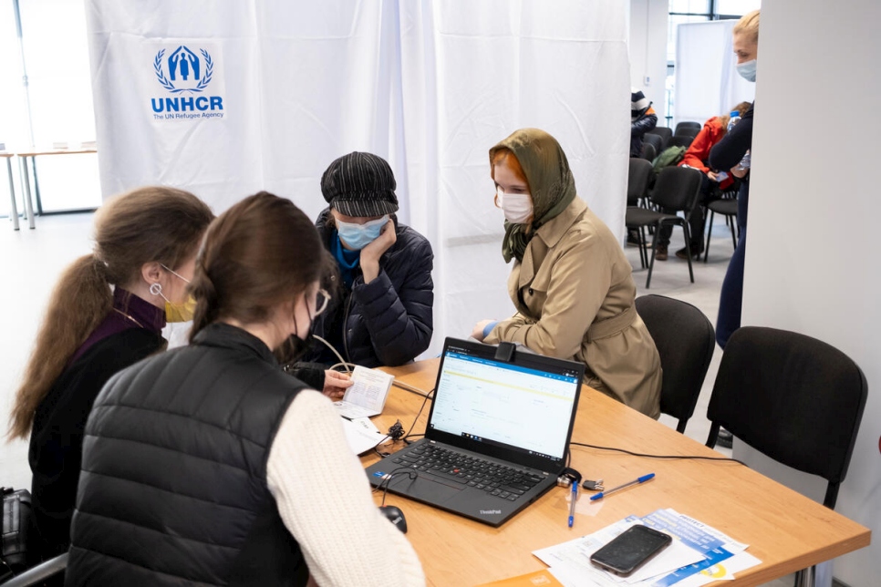 Personas refugiadas de Ucrania se registran para recibir asistencia económica en efectivo en un centro de ACNUR en Varsovia, Polonia.