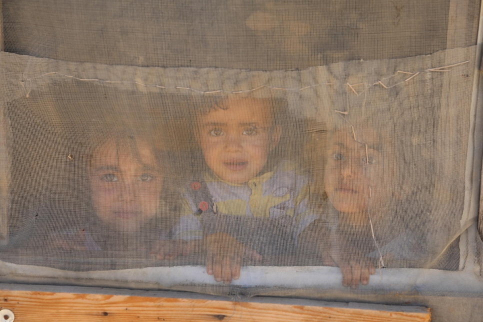 Niños sirios refugiados miran por la ventana de su alojamiento en un asentamiento informal en el Valle de la Bekaa, en el Líbano.