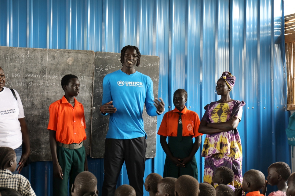 Wenyen Gabriel, exrefugiado sursudanés y jugador de Los Angeles Lakers, habla con niñas y niños desplazados en la pequeña escuela primaria del campamento de personas desplazadas internas de Mangalla.
