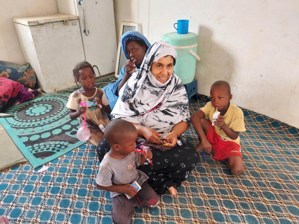 Una vecina visita la casa de Mohamed trayendo bocadillos y jugos para sus hijos.