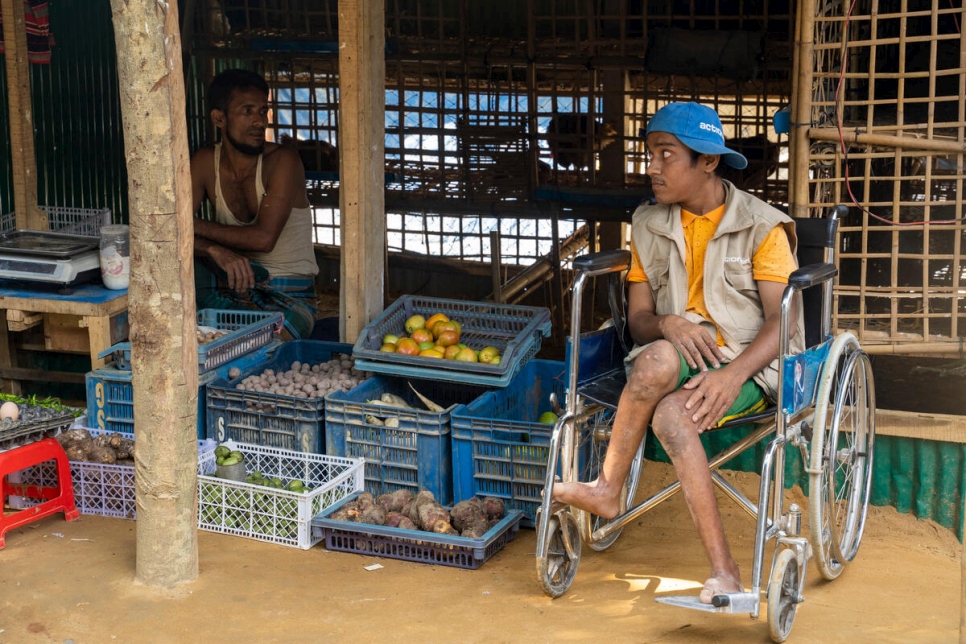 Nur está sentado en una tienda de vegetales en el mercado de Kutupalong, donde divulga información recogida en el centro comunitario local.