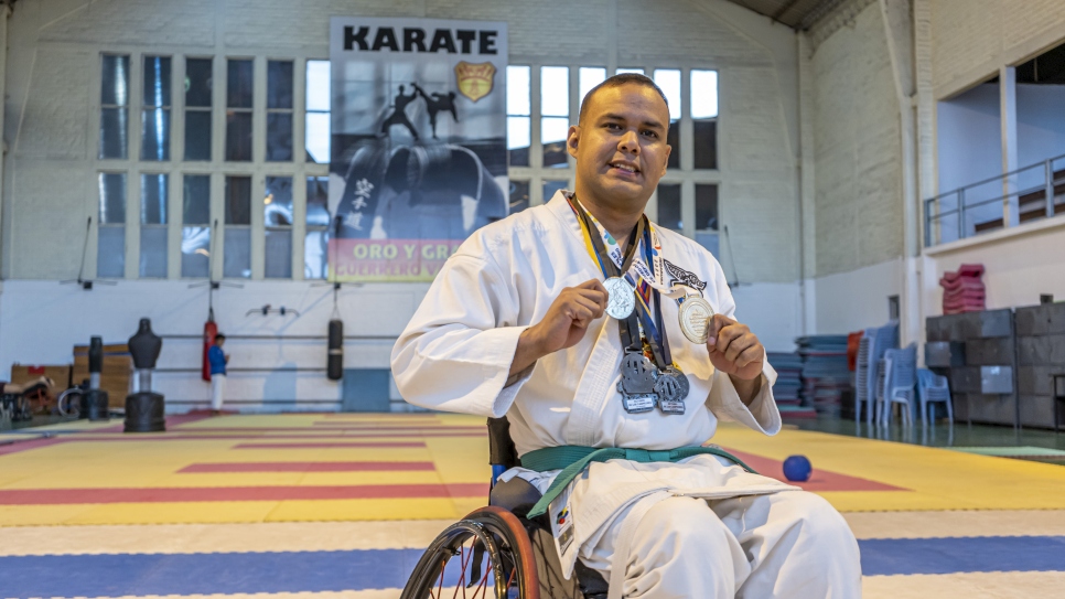 Carlos Acosta, refugiado venezolano, sostiene las medallas que ha ganado en competiciones de para-karate después de un entrenamiento en Quito.