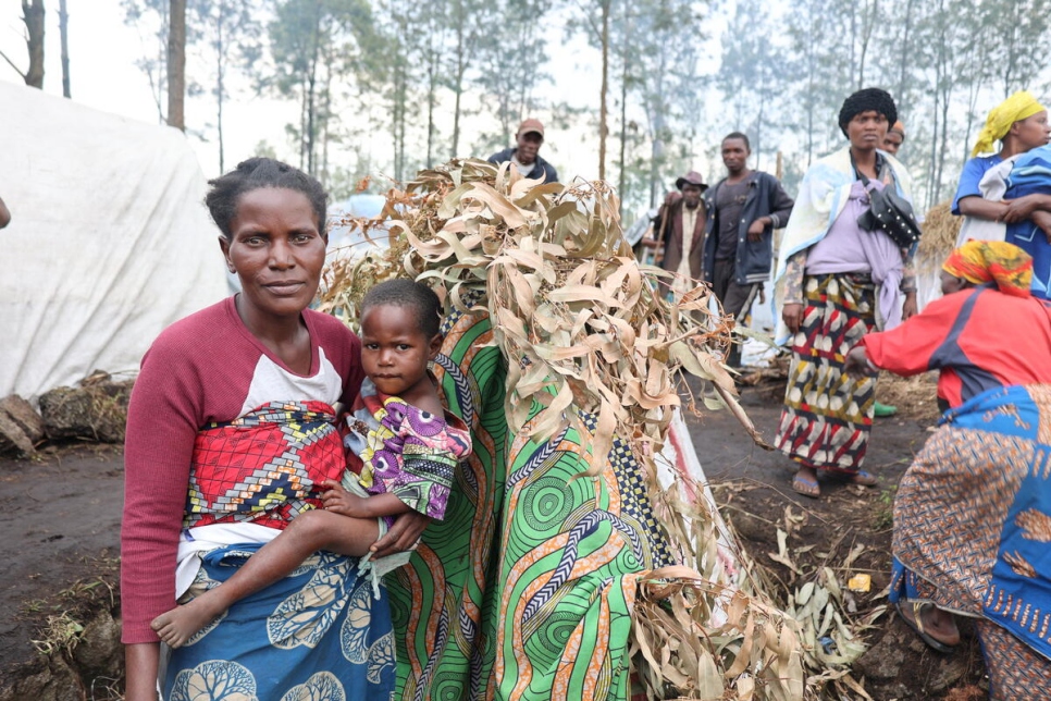 Feza Tulinabo, madre desplazada con ocho hijos, al lado del alojamiento que ella misma construyó en un nuevo asentamiento para personas desplazadas internas en Rusayu, Kivu del Norte.