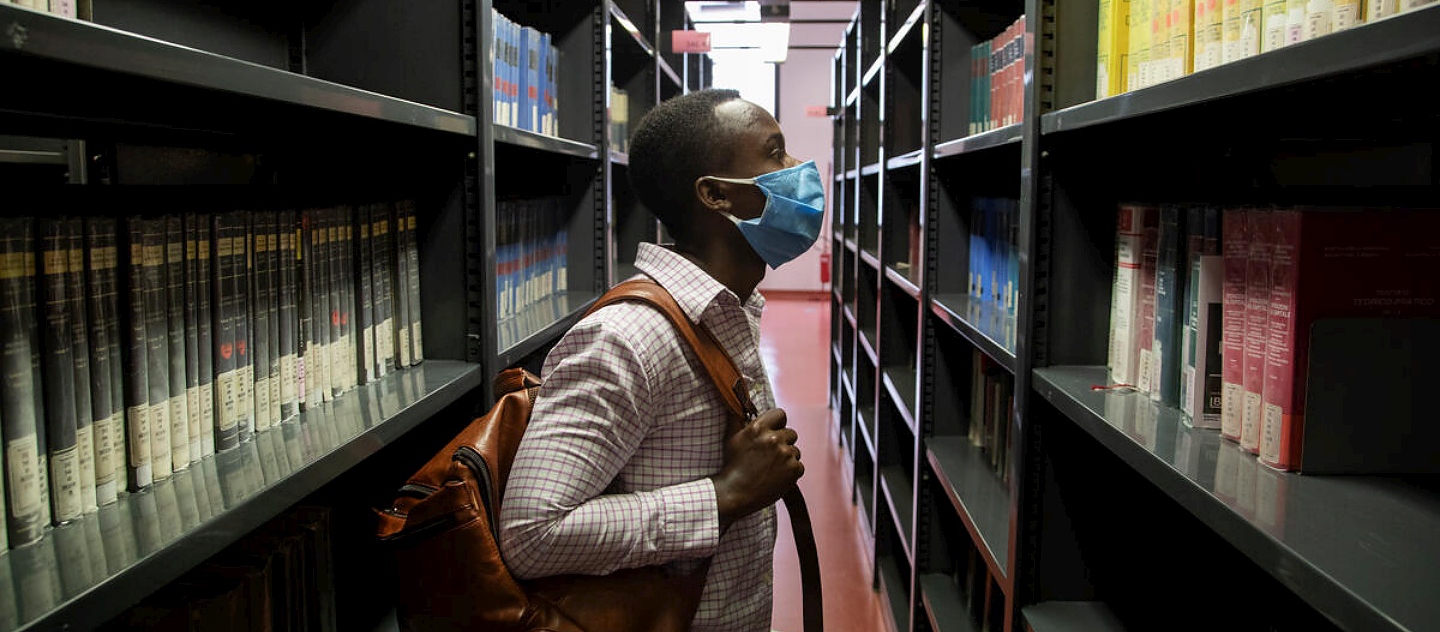 Jules, un estudiante de 26 años de la República Democrática del Congo, explora los estantes de la biblioteca de ciencias sociales de la Universidad de Florencia.