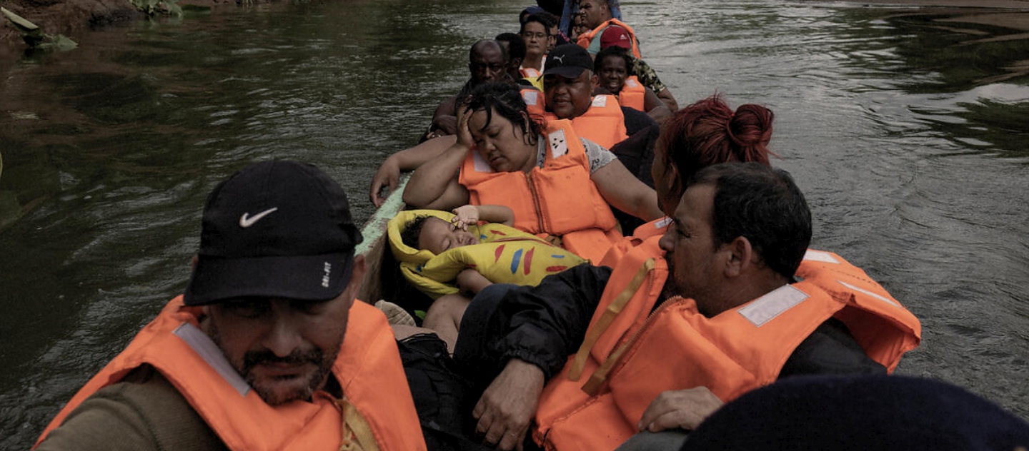 Personas refugiadas y migrantes de Cuba, Haití y Venezuela toman una canoa después de cruzar la selva del Darién para llegar a Panamá.
