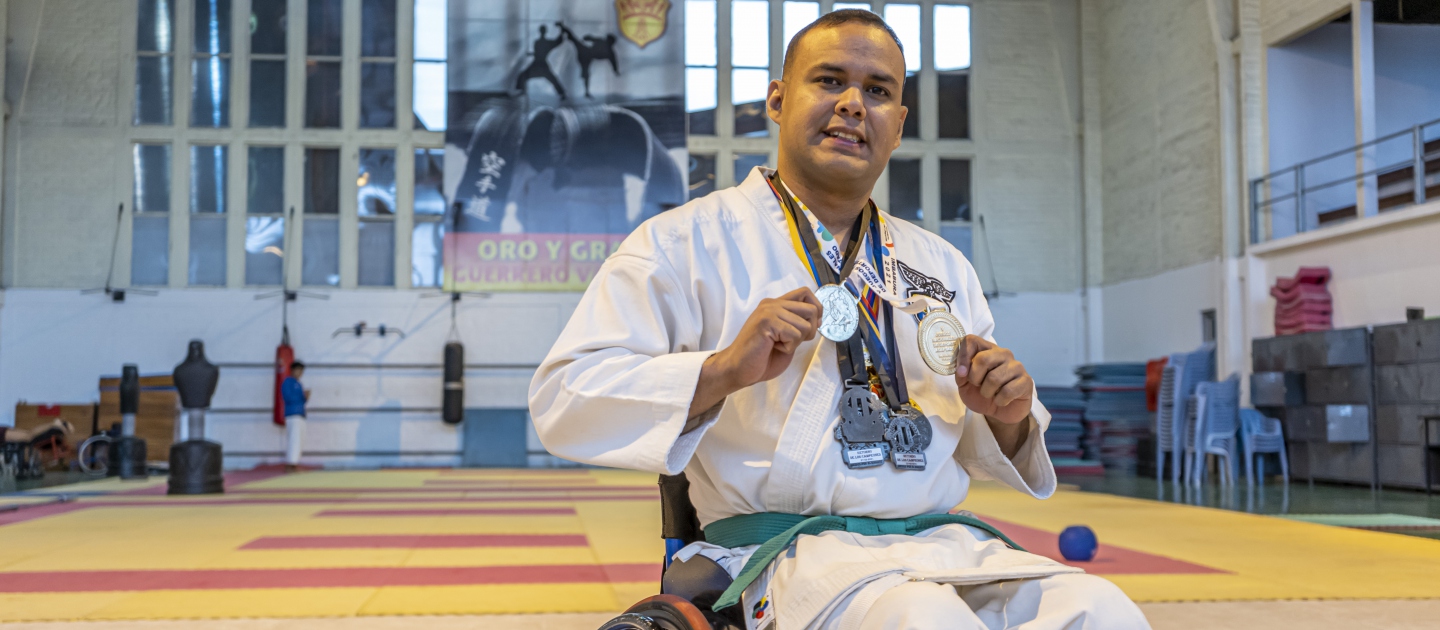 Carlos Acosta, refugiado venezolano, sostiene las medallas que ha ganado en competiciones de para-karate después de un entrenamiento en Quito.