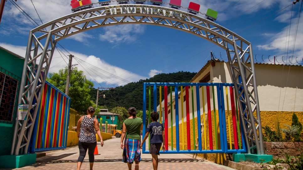 Una familia entra en las puertas de un centro diurno administrado por el gobierno en Santa Ana, El Salvador, que ofrece talleres y capacitaciones a los adolescentes y les proporciona un espacio seguro lejos de la vida de pandillas.