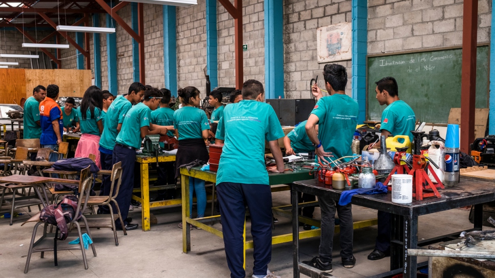 Un grupo de jóvenes aprende cómo reparar un motor en un taller de mecánicos de automóviles en un centro gubernamental juvenil y comunitario en Santa Ana, El Salvador.
