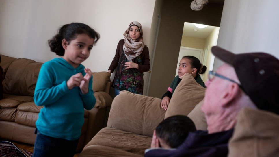 El patrocinador Michael Adams (a la derecha) visita a la familia Numan en su hogar en Toronto. La familia Numan se encuentra entre los 13.000 refugiados reasentados en Canadá a lo largo del pasado año.