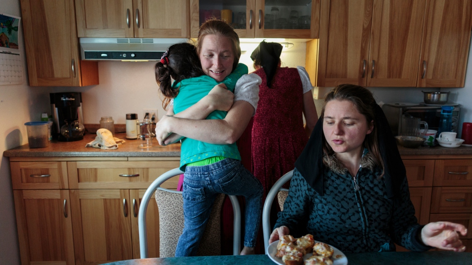 Elaine Hofer (izquierda) abraza a Raghad, la hija mayor de la familia Al Hamoud, mientras Alice Hofer y Wanda Waldner preparan comida para los niños.