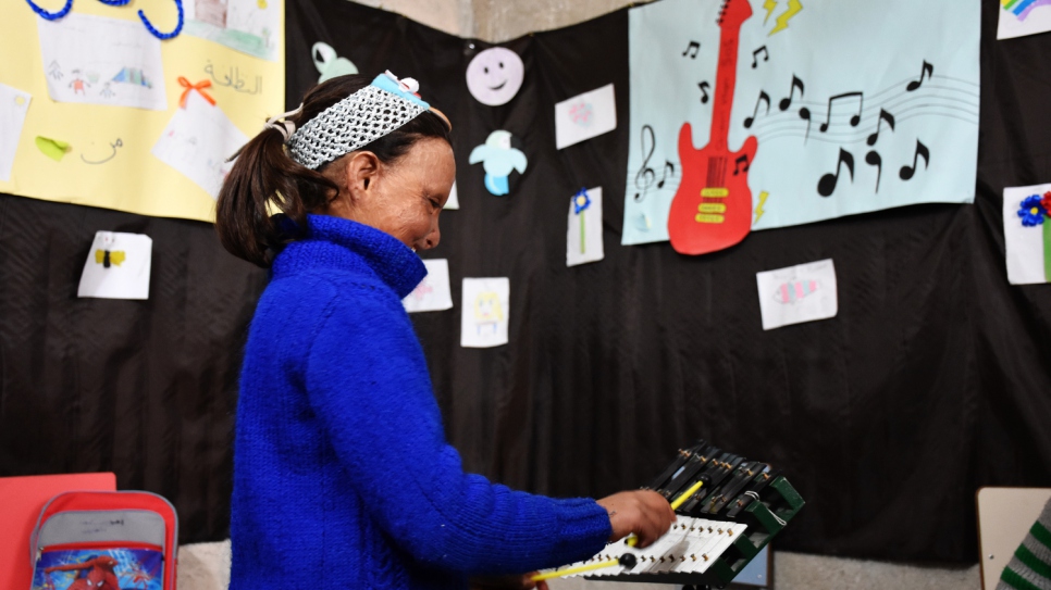 Wafaa toca música en un aula en el albergue temporal, donde finalmente ha podido comenzar su educación y asistir a la escuela por primera vez.