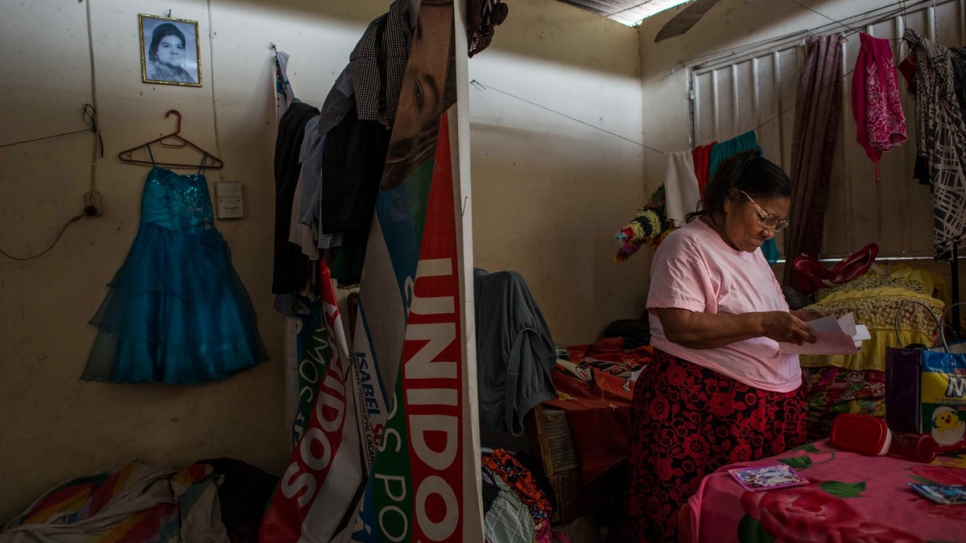María mira fotos de familia en su habitación en el sur de México. El vestido colgado en la pared pertenecía a su bisnieta, María Luz, quien fue asesinada por un pandillero en El Salvador.