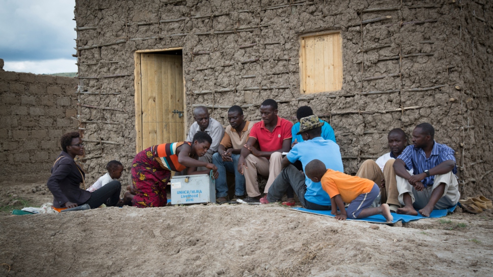 Janine, refugiada congoleña abre la caja donde el grupo de piscicultura del lago Rwamunga, en el distrito de Isingiro, en Uganda, guarda su dinero para contar los ahorros y garantizar los préstamos a sus miembros. El grupo se reúne una vez por semana en casa de Janine.