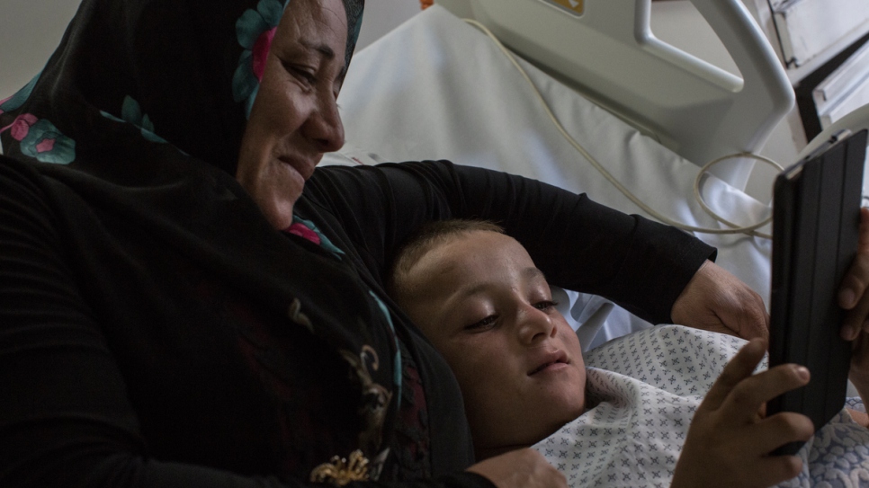 Issam mira un iPad con su madre, Badriyeh al lado, antes de ser sometido a la operación quirúrgica en el Hospital del Sacre Coeur.