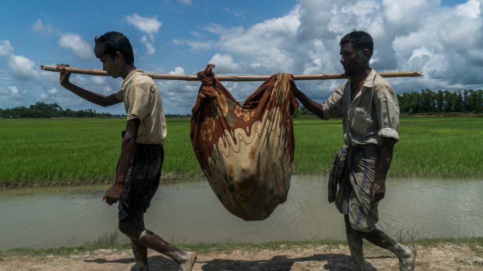 Mabia Khatun (imperceptible dentro de la manta), de 75 años, es cargada por dos de sus hijos después de cruzar de Myanmar, cerca de Whaikhyang, Bangladesh.