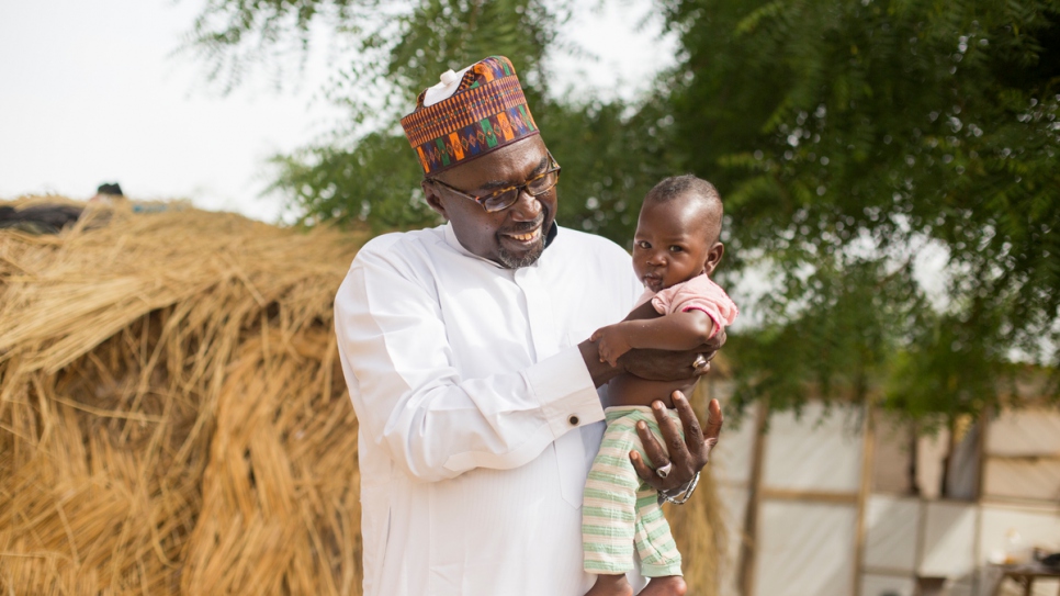 Mustapha sostiene en brazos al pequeño Zannah, llamado así en su honor por desplazados que viven cerca de la segunda escuela que fundó en Maiduguri, estado de Borno, Nigeria.