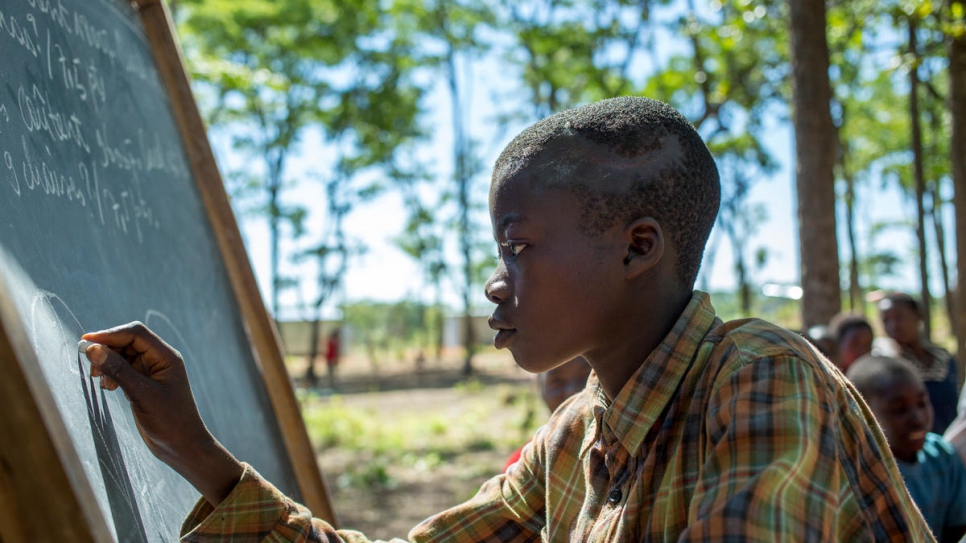 El estudiante refugiado Richard Nduwimana, un niño de 13 años de Burundi, escribiendo en la pizarra.