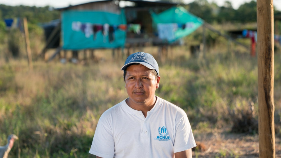 El oficial de ACNUR Harold Juajibioy Otero frente a una de las casa del asentamiento awá de Villagarzón. La Agencia de la ONU para los Refugiados apoya el empoderamiento de la comunidad y la reconstrucción del territorio indígena.