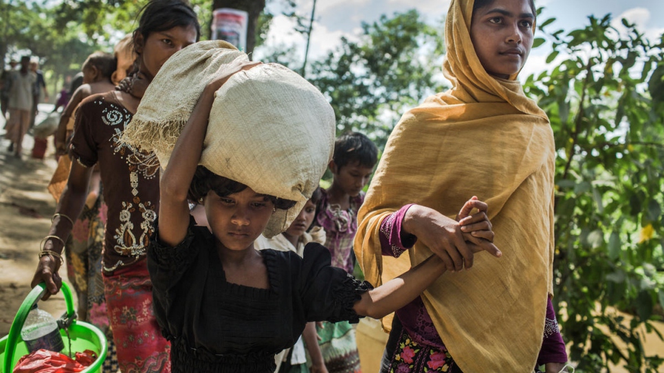 Rabiaa Khatun, de dieciocho años, y su sobrina, Umme Salma, de 8 años, caminan a 10 kilómetros de la frontera con Myanmar hasta un campamento de tránsito de ACNUR en Kutupalong, Bangladesh.