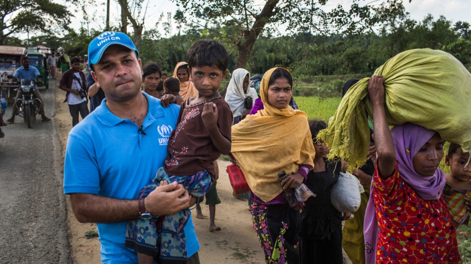 Mohammed Abu Asaker, portavoz de ACNUR, lleva en brazos a Noor Kalima, de 4 años, durante una caminata de 10 kilómetros entre la frontera de Myanmar y el campo de refugiados de Kutupalong, en Bangladesh. Los padres de Noor fueron asesinados durante el ataque a su pueblo. Tanto ella como su Hermana, Umme Salma (de negro), están bajo el cuidado de su tía, Rabiaa Khatun (con velo naranja).