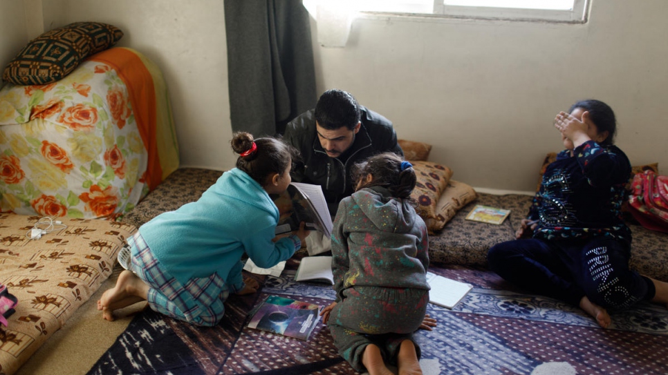 Después de su turno en la fábrica, Mohammed Jamal Kabour, refugiado sirio de 33 años, ayuda a sus hijas con las tareas escolares.